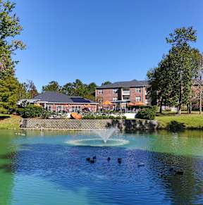 a fountain in the middle of a pond with a building in the background at Jamison Park Apartments in North Charleston, SC 29406
