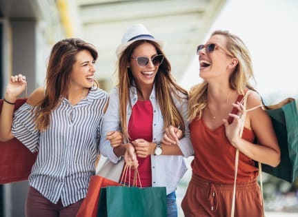 three women walking down the street with shopping bags