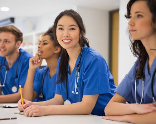 A group of medical professionals in blue scrubs are sitting at a table.