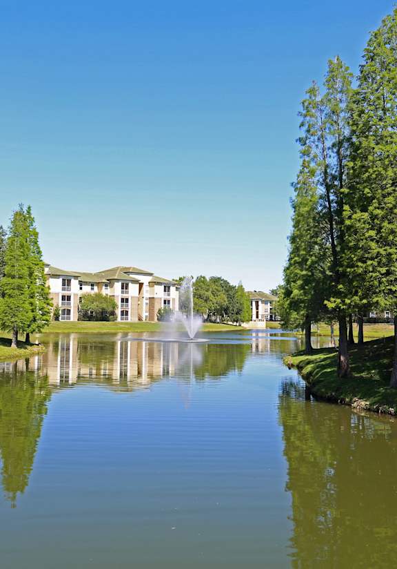 a pond with a fountain in front of a house