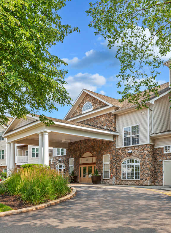 the residences at the estates at sunset with flowering plants in front of the building at Highlands at Faxon Woods, Quincy, Massachusetts