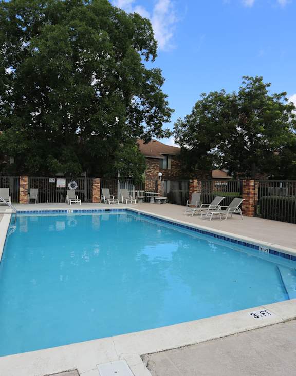 A swimming pool surrounded by a fence and trees.