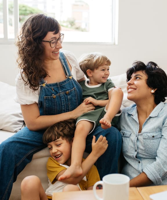 a mother and her two children are sitting on a couch with a laptop