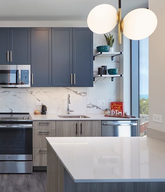 A modern kitchen with dark blue cabinets and stainless steel appliances.