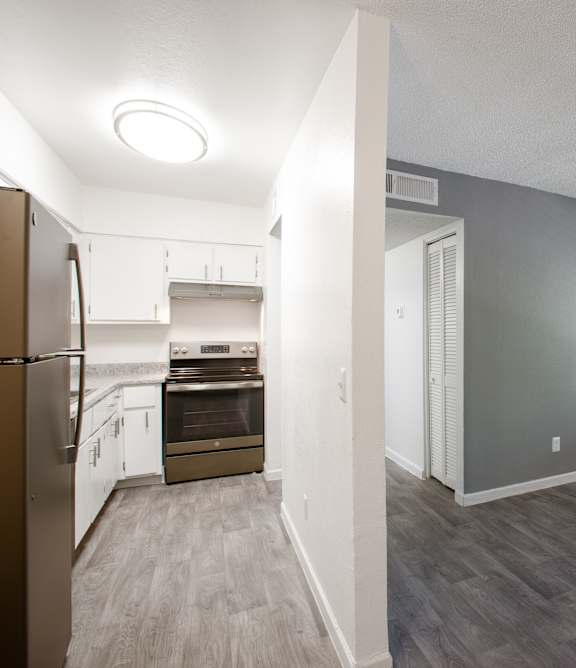 A kitchen with a refrigerator, oven, and cabinets.