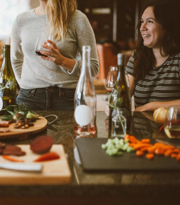 a group of women standing around a table with food and drinks