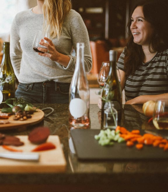 a group of women standing around a table with food and drinks