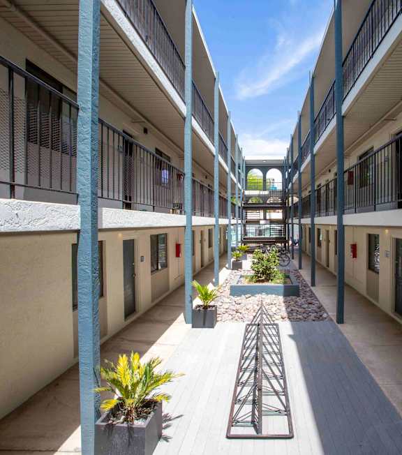 A long hallway with a metal railing and potted plants.