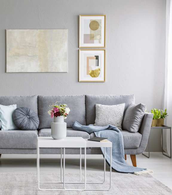 A grey sofa with a white coffee table in front of it.