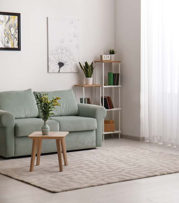 A living room with a green couch, a wooden table, and a plant on it.
