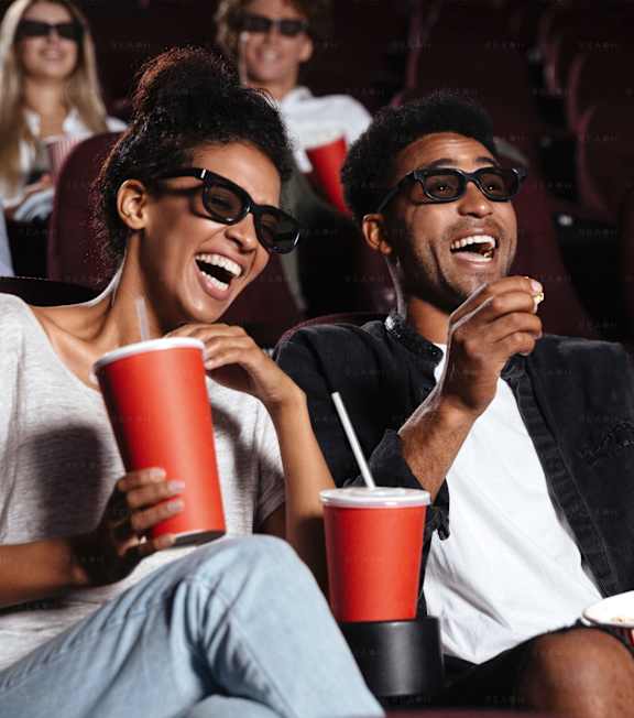 a group of people laughing and eating popcorn at a movie theater