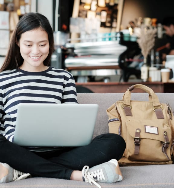a woman sitting on a couch using a laptop computer
