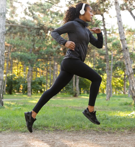 a woman running in a park with headphones