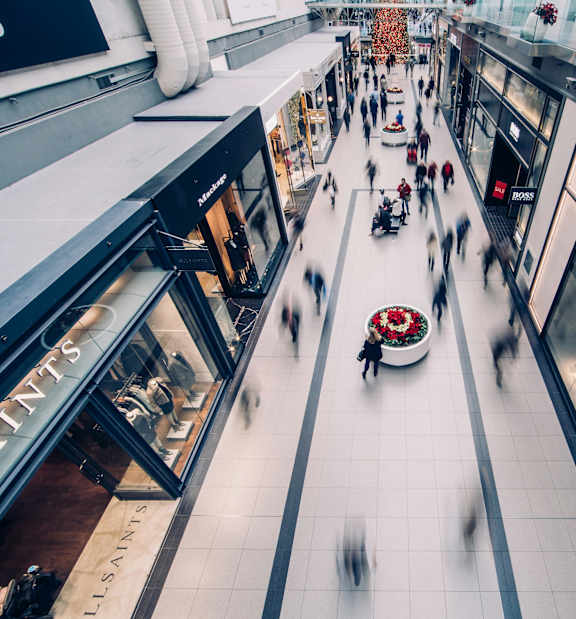 A blurry image of a shopping mall with people walking.
