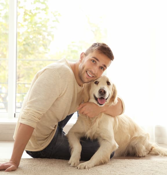 a man sitting on the floor with a dog at Altis Twin Lakes Apartments, Kissimmee, FL 34744