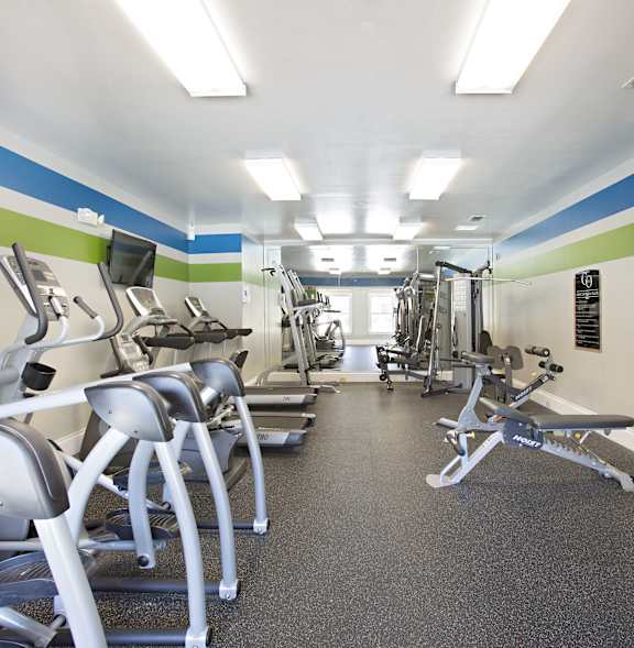 A gym with a variety of equipment including treadmills, weights, and exercise machines.