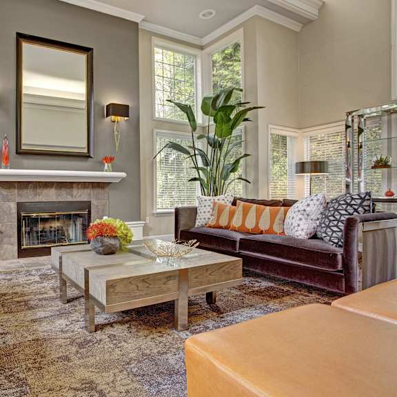 The resident lounge at Aspen Creek with couches, a coffee table, and a fireplace. 