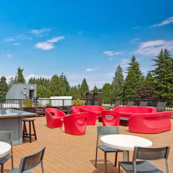 The rooftop balcony lounge with couches, chairs, coffee tables, and potted plants at Leilani Apartment Homes. 