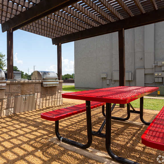 A picnic table with red benches is set up under a wooden pergola.