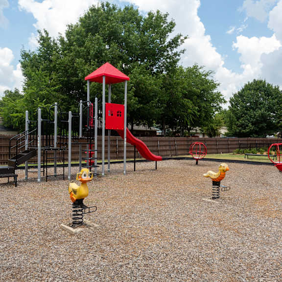 A playground with a red swing set and yellow slides.