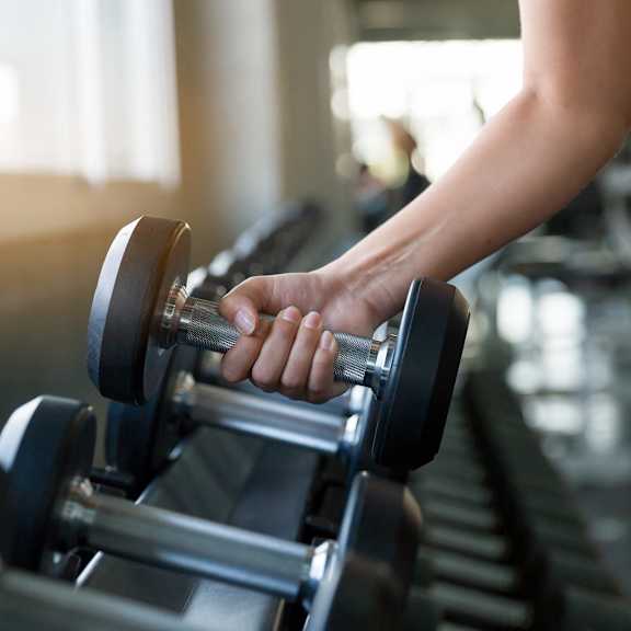 a woman holding dumbbells on a treadmill in a gym at Creekside Canopy, Charlotte, NC
