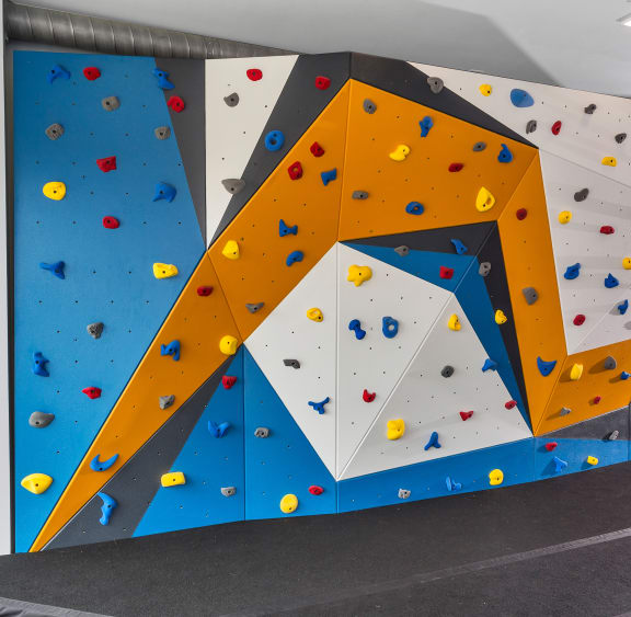 a large climbing wall in a room with a ramp and stairs