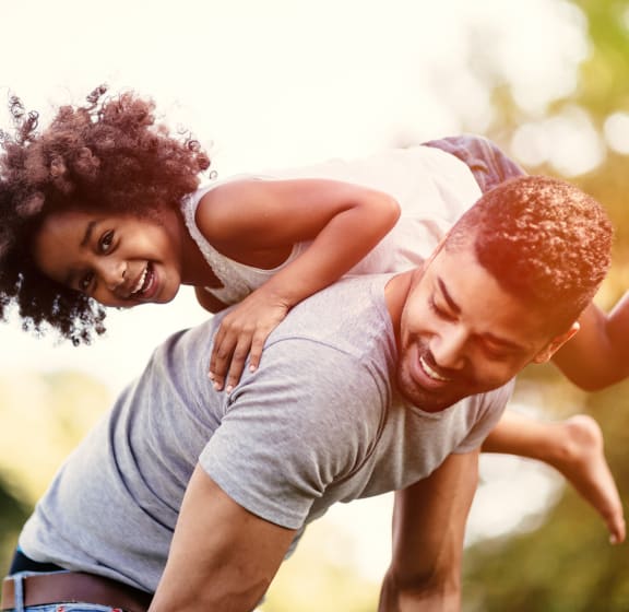 a young girl rides on the back of a man at Zeta Luxury Apartments in Sacramento, CA