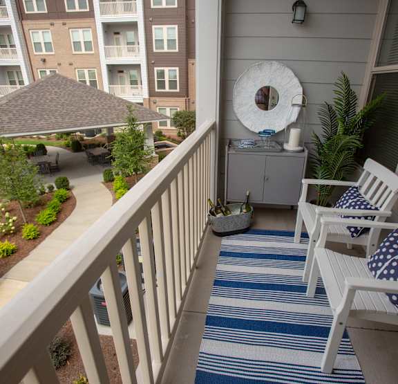 A balcony with two chairs and a table with a plant on it.