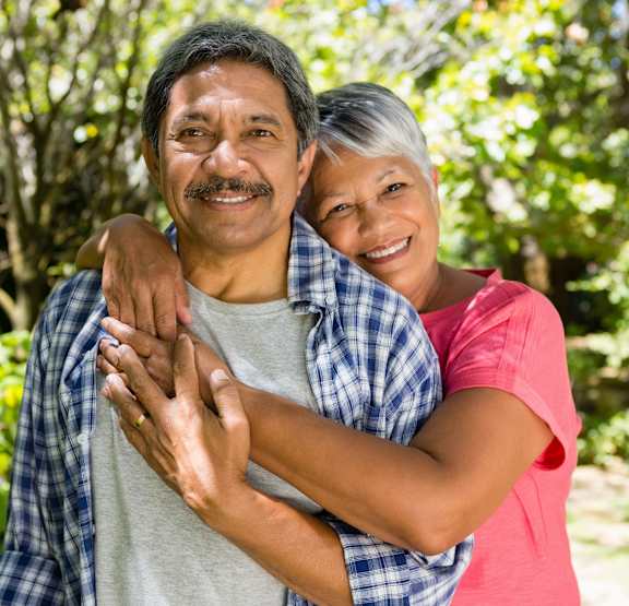 A man and woman are hugging each other in a garden.