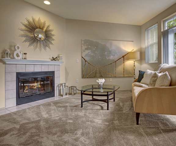 An empty living room with a dog bed and a kitchen in the background at Aspen Creek. 