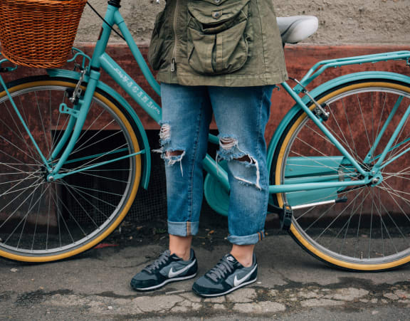 a woman standing next to a blue bike