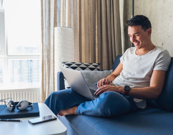 a man sitting on a couch using a laptop computer
