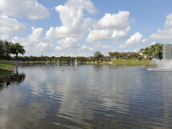 A fountain in the middle of a lake with a cloudy sky above.