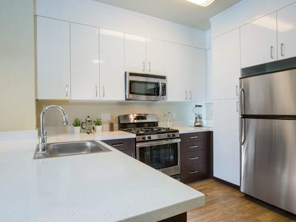 A modern kitchen with a stainless steel refrigerator and a white countertop.