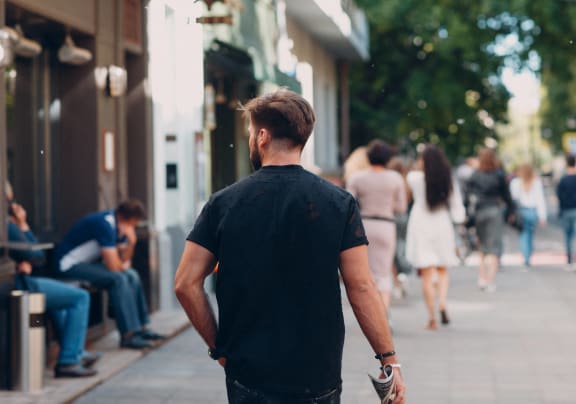 a man walking down a sidewalk with his hands in his pockets