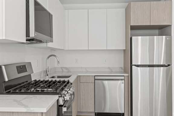 A modern kitchen with a stainless steel refrigerator, microwave, and dishwasher.