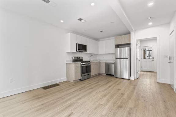 A modern kitchen with wooden floors and stainless steel appliances.