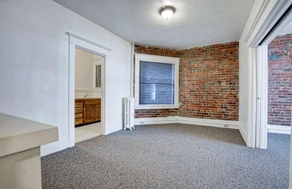 A room with a brick wall and a window.