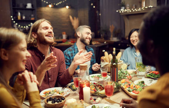 a group of people sitting around a dinner table talking and laughing at The Heritage at Arlington Apartment Homes, Greenville, NC 27834
