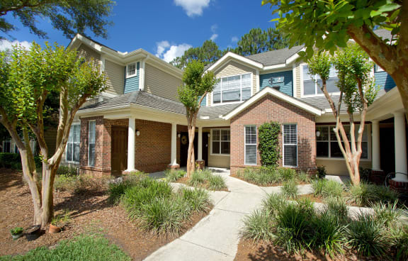 a house with a sidewalk and trees in front of it