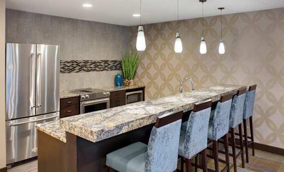 A kitchen with a marble countertop and bar stools.