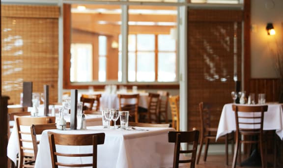 an empty restaurant with white tables and chairs