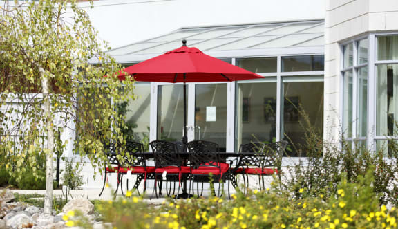 Outside seating area with red umbrella and red chairs. 