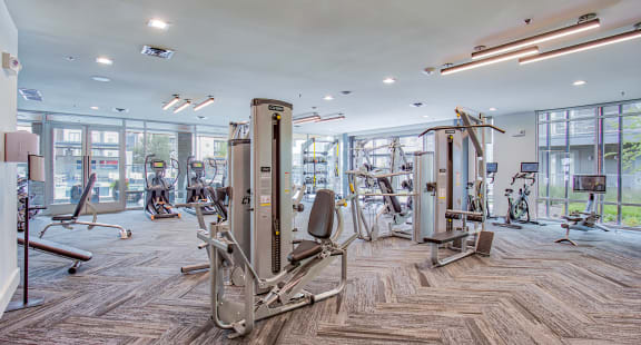 a gym with cardio machines and weights in a building with large windows at Presidium Revelstoke, Texas
