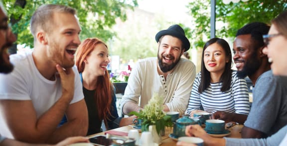 a group of people sitting around a table talking and laughing