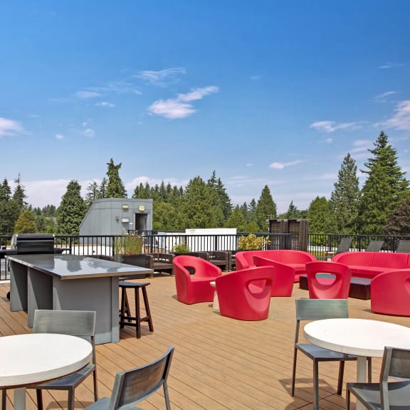 a rooftop deck with tables and chairs and a grill