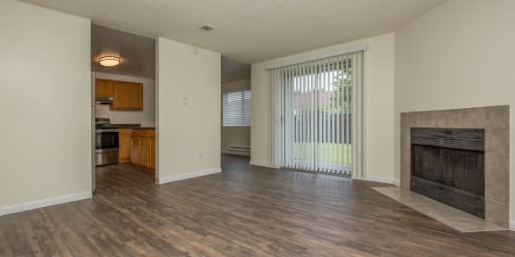 a living room with a fireplace and a kitchen in the background