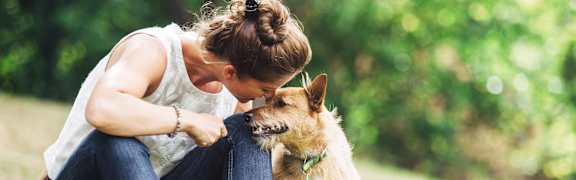 A woman is sitting on the grass with her dog.