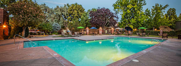 A swimming pool surrounded by trees and lounge chairs.