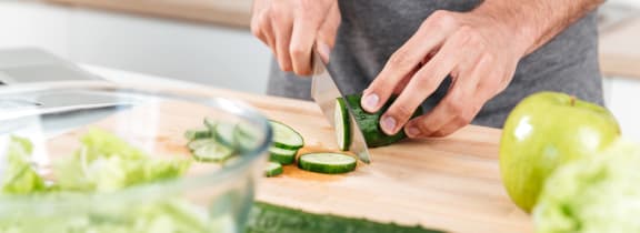 a man cutting cucumbers on a cutting board